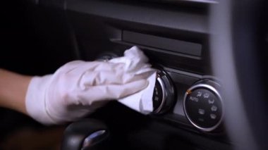 Beyaz eldivenli el spreyleme ve cam yüzeyi silme, arabanın ön camını silme, dezenfektan bezi, Covid-19 Corona virüsü, araba bakımı, anti bakteri, hijyen yaşam tarzı, sabah ışığı.