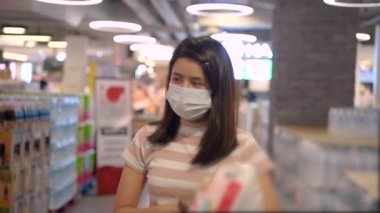 Genç Asyalı kadın markette Corona krizi sırasında alışveriş yaparken maske takıyor, yiyecek stokluyor, covid19 salgını, plastik torbaya, el havlusuna, tuvalet kağıdına ve tuvalet kağıdına hayır diyor.