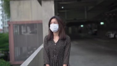 Şehirde tıbbi maske takan Asyalı genç bir kadın.