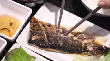 4k Asya sağlıklı yiyecekler, yemek çubuklarıyla insan elini kapatın ızgara balık, Asya mutfağı, beslenme diyeti, omega 3, yeşil sebze, kapalı restoran, Asya geleneği, Japon tarzı.