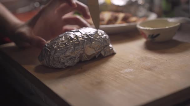 スローモーション手を使用してナイフを開くものホイル焼きポテト 自家製家庭料理のコンセプト 家庭で木の板の上に焼きジャガイモを提出 食品成分商業 調理ディナー 秘密のレシピ — ストック動画