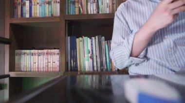 4K ofis çalışanı oturmuş akıllı telefonunu kontrol ediyor. Çalışan bir kafede çalışıyor. Serbest çalışan eski bir ev, gövde çekimi, modern bir yaşam tarzı.