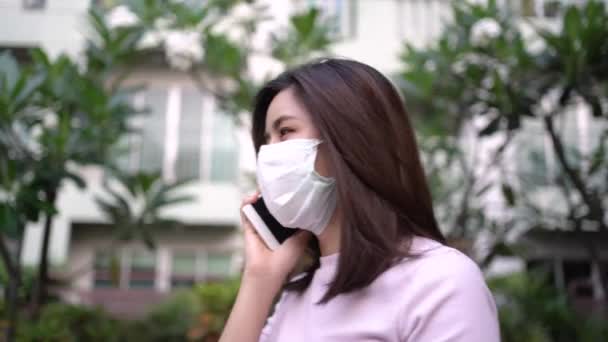 4K亚洲妇女在电话交谈时戴面具 严重的谈话问题 危险疾病和空气污染 病毒感染 呼吸道疾病 公寓外 — 图库视频影像