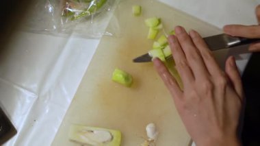 Beyaz tahtada sebze kesen kadın.