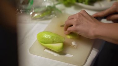 Beyaz tahtada sebze kesen kadın.