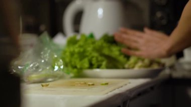 Kadın mutfak masasında taze salata hazırlıyor.