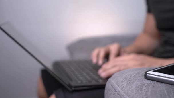 在家里和笔记本电脑一起工作的男人 网络连接 坐在键盘上打字的新的正常的现代生活方式男人 自我隔离沙发坐着 模糊的背景 — 图库视频影像