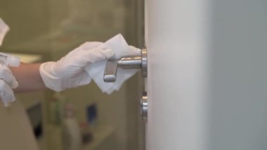 Kadın koruyucu beyaz eldiven veriyor banyonun kapı kolunu temizliyor, beyaz renkli kapı, dezenfektan, koronavirüsü önlüyor, kovid19, dezenfeksiyon, ev temizleyici anti bakteri mendilleri, mikropları öldürüyor.