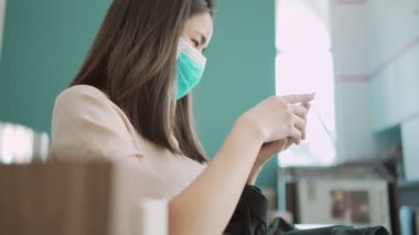 4K Asyalı kadın akıllı telefon kullanarak maske takıyor, kadın elinde cep telefonu, internet üzerinden sağlık makaleleri okuyor, hastalıklardan, sosyal sorunlardan, sağlık sorunlarından, hayat sigortası reklamlarından kendini sakınıyor
