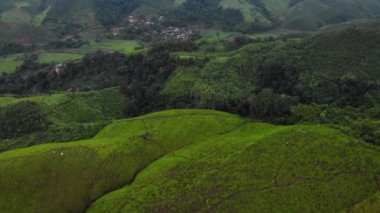 4k açılı insansız hava aracı büyük yeşil dağın, yüksek irtifanın, sisli, bulutların arasından geçen güneş ışığı, soğuk ve serin hava, kış yağmuru mevsimi, tropikal iklim