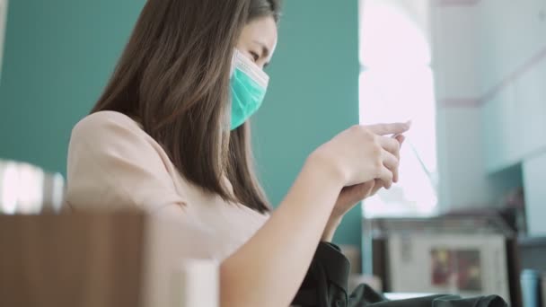4K亚洲女性戴口罩使用智能手机 女性坐下来手持手机阅读网上保健品 自我预防疾病 社会问题 健康问题 人寿保险商业广告 — 图库视频影像