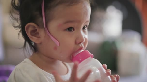 アジアの女の子の手に牛乳のボトルを吸い 小さな子供の開発 幼児ボトルから牛乳を飲む 幼児の公式ミルク 1つのアジアの良いかわいい女性に見える — ストック動画