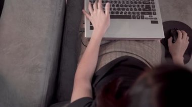 Yukarıda Asyalı çalışan bir kadının bilgisayar laptopu kullanması, evdeki koltukta oturması, karantina süresince evden çalışması, kişisel izolasyon süreci, finansal işler, üst görüş.