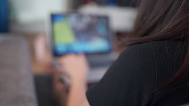 ラップトップのぼやけたショットを介してアジアの女性のコンピュータゲームをプレイ 自宅で ソファに座って ホームエンターテイメント 自宅の隔離 リラクゼーションレジャー活動 コンピュータソフトウェア ウイルススキャナ検出 — ストック動画