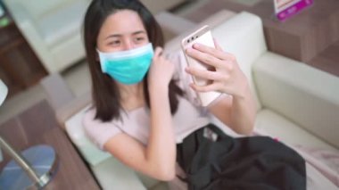 Asya 'lı Kadın, maske takarken videoyu izledi, yeni normal yaşam tarzı, yaşam ilişkisi teması, kovid-19 sırasında, izolasyon karantinasını görüntülü aradı. Sosyal uzaklık, aile kaliteli zaman, yukarıda