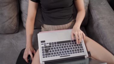Asyalı genç kadın serbest çalışıyor. Koltukta oturuyor, sosyal çalışma mesafesi, kişisel çalışma, online eğitim kursu programı, verimli gün rutini, çevrimiçi sörf. 