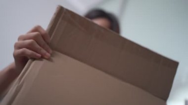 Karton kutuları açan Asyalı kadın, kadın paketi açıyor, çevrimiçi alışveriş teslimatı, paketleri açıyor koltukta oturuyor, arka planı bulanık, yeni normal hayat tarzı, ev karantinası.
