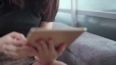 Tablet kullanan kadın oturma odasında oturuyor, kablosuz ağ bağlantısı, ev karantinası, öz disiplin, online alışveriş, gündüz vakti doğal ışık, internet taraması, bilgi araştırması