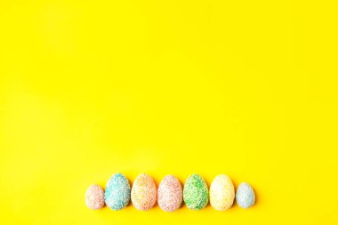 Sarı arka planda pastel yumurtalar ve metin için boşluk. Mutlu Paskalyalar.