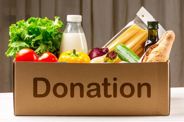 Caja de donaciones con varios alimentos. Caja de cartón abierta con aceite, verduras, leche, conservas, cereales y pasta. Concepto de entrega — Foto de Stock