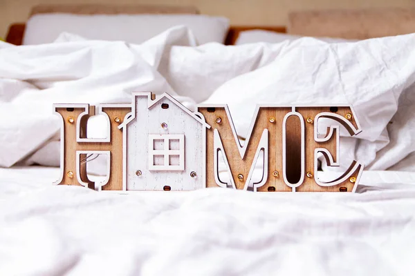 COVID-19 Coronavirus stay home save lives viral social media message sign with text for social distancing awareness. Staying at home concept. Wooden house inscription home on bed.