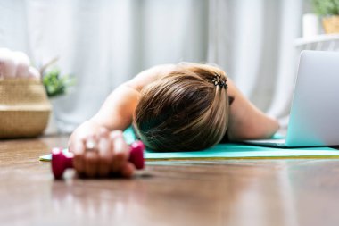 Kadın uykuya dalıyor. Egzersiz ve egzersizden sonra yorgun. Aşırı eğitim konsepti. Yoga minderindeki yoğun kardiyo eğitiminden sonra yerde yatan bitkin bir kadın.