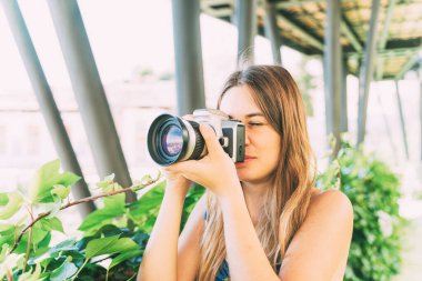 Analog kamera ve bulanık arka planla fotoğraf çeken genç bir kadın..