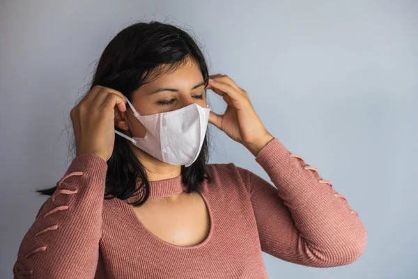Pembe kazaklı bir kadın koronavirüs için maske takıyor.