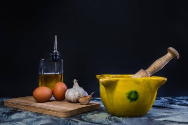 Bowl of garlic and oil sauce with eggs, oil and garlic on black background composition clipart
