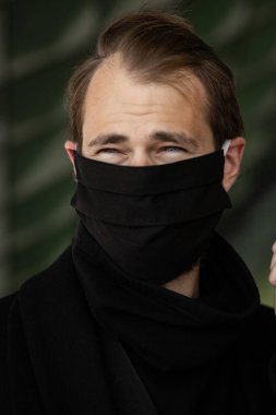 Şehrin sokaklarında maske takan yakışıklı bir adam. Grip virüsü veya koronavirüs enfeksiyonuna karşı korunmak için solunum cihazına bağlı bir gencin yakın çekimi.