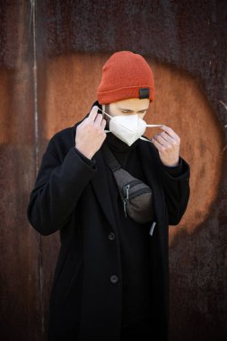 Şehrin sokaklarında maske takan yakışıklı bir adam. Grip virüsü veya koronavirüs enfeksiyonuna karşı korunmak için solunum cihazına bağlı bir gencin yakın çekimi.