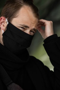 Şehrin sokaklarında maske takan yakışıklı bir adam. Grip virüsü veya koronavirüs enfeksiyonuna karşı korunmak için solunum cihazına bağlı bir gencin yakın çekimi.