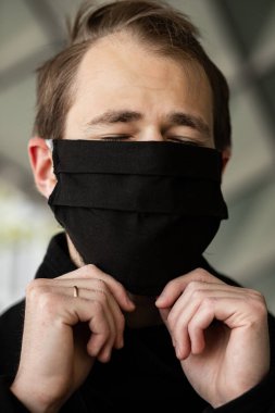 Şehrin sokaklarında maske takan yakışıklı bir adam. Grip virüsü veya koronavirüs enfeksiyonuna karşı korunmak için solunum cihazına bağlı bir gencin yakın çekimi.