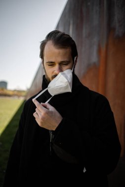 Şehrin sokaklarında maske takan yakışıklı bir adam. Grip virüsü veya koronavirüs enfeksiyonuna karşı korunmak için solunum cihazına bağlı bir gencin yakın çekimi.