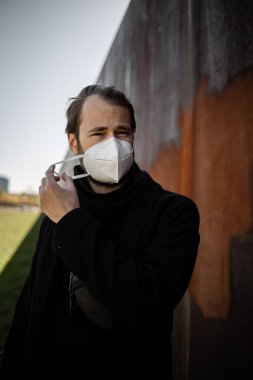 Şehrin sokaklarında maske takan yakışıklı bir adam. Grip virüsü veya koronavirüs enfeksiyonuna karşı korunmak için solunum cihazına bağlı bir gencin yakın çekimi.