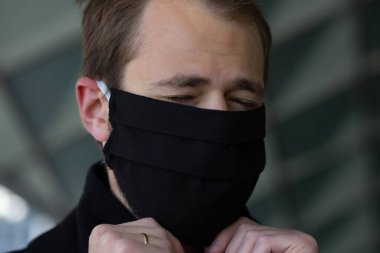 Şehrin sokaklarında maske takan yakışıklı bir adam. Grip virüsü veya koronavirüs enfeksiyonuna karşı korunmak için solunum cihazına bağlı bir gencin yakın çekimi.