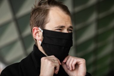 Şehrin sokaklarında maske takan yakışıklı bir adam. Grip virüsü veya koronavirüs enfeksiyonuna karşı korunmak için solunum cihazına bağlı bir gencin yakın çekimi.