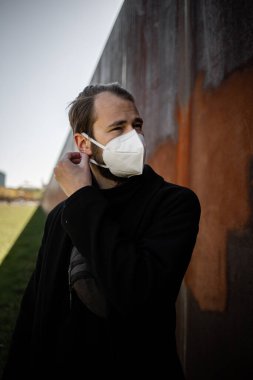 Şehrin sokaklarında maske takan yakışıklı bir adam. Grip virüsü veya koronavirüs enfeksiyonuna karşı korunmak için solunum cihazına bağlı bir gencin yakın çekimi.