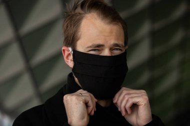 Şehrin sokaklarında maske takan yakışıklı bir adam. Grip virüsü veya koronavirüs enfeksiyonuna karşı korunmak için solunum cihazına bağlı bir gencin yakın çekimi.