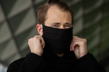Şehrin sokaklarında maske takan yakışıklı bir adam. Grip virüsü veya koronavirüs enfeksiyonuna karşı korunmak için solunum cihazına bağlı bir gencin yakın çekimi.