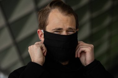 Şehrin sokaklarında maske takan yakışıklı bir adam. Grip virüsü veya koronavirüs enfeksiyonuna karşı korunmak için solunum cihazına bağlı bir gencin yakın çekimi.