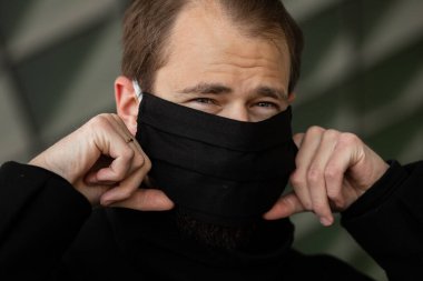 Şehrin sokaklarında maske takan yakışıklı bir adam. Grip virüsü veya koronavirüs enfeksiyonuna karşı korunmak için solunum cihazına bağlı bir gencin yakın çekimi.