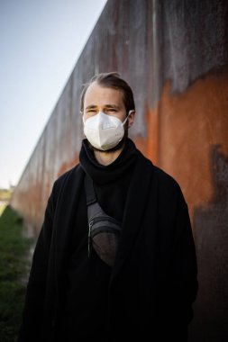 Şehrin sokaklarında maske takan yakışıklı bir adam. Grip virüsü veya koronavirüs enfeksiyonuna karşı korunmak için solunum cihazına bağlı bir gencin yakın çekimi.