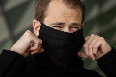 Şehrin sokaklarında maske takan yakışıklı bir adam. Grip virüsü veya koronavirüs enfeksiyonuna karşı korunmak için solunum cihazına bağlı bir gencin yakın çekimi.
