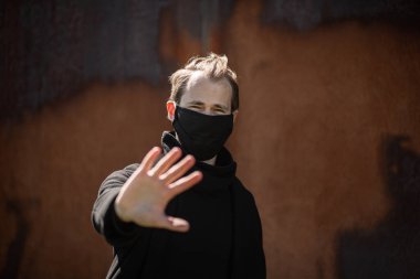 Şehrin sokaklarında maske takan yakışıklı bir adam. Grip virüsü veya koronavirüs enfeksiyonuna karşı korunmak için solunum cihazına bağlı bir gencin yakın çekimi.