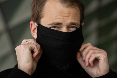 Şehrin sokaklarında maske takan yakışıklı bir adam. Grip virüsü veya koronavirüs enfeksiyonuna karşı korunmak için solunum cihazına bağlı bir gencin yakın çekimi.