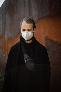 Şehrin sokaklarında maske takan yakışıklı bir adam. Grip virüsü veya koronavirüs enfeksiyonuna karşı korunmak için solunum cihazına bağlı bir gencin yakın çekimi.