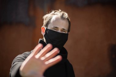 Şehrin sokaklarında maske takan yakışıklı bir adam. Grip virüsü veya koronavirüs enfeksiyonuna karşı korunmak için solunum cihazına bağlı bir gencin yakın çekimi.