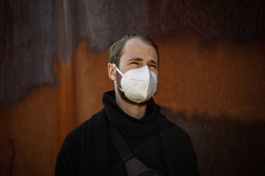 Şehrin sokaklarında maske takan yakışıklı bir adam. Grip virüsü veya koronavirüs enfeksiyonuna karşı korunmak için solunum cihazına bağlı bir gencin yakın çekimi.