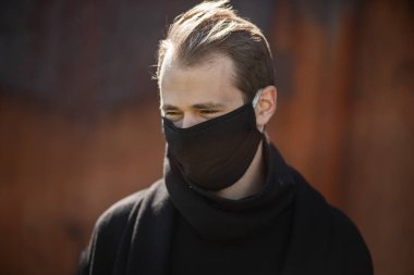 Şehrin sokaklarında maske takan yakışıklı bir adam. Grip virüsü veya koronavirüs enfeksiyonuna karşı korunmak için solunum cihazına bağlı bir gencin yakın çekimi.